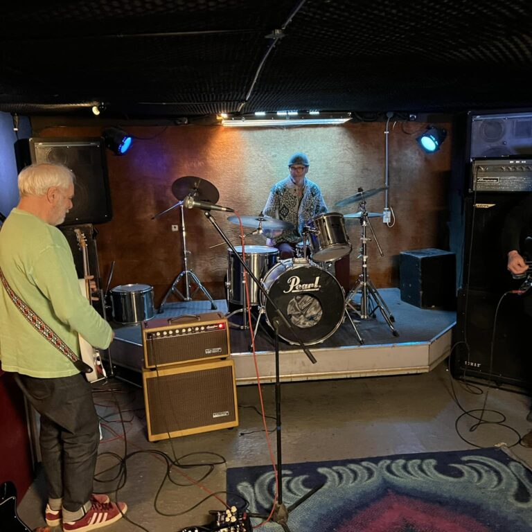 Muzikanten in de oefenruimte van Stichting UFO, met een drummer op het podium