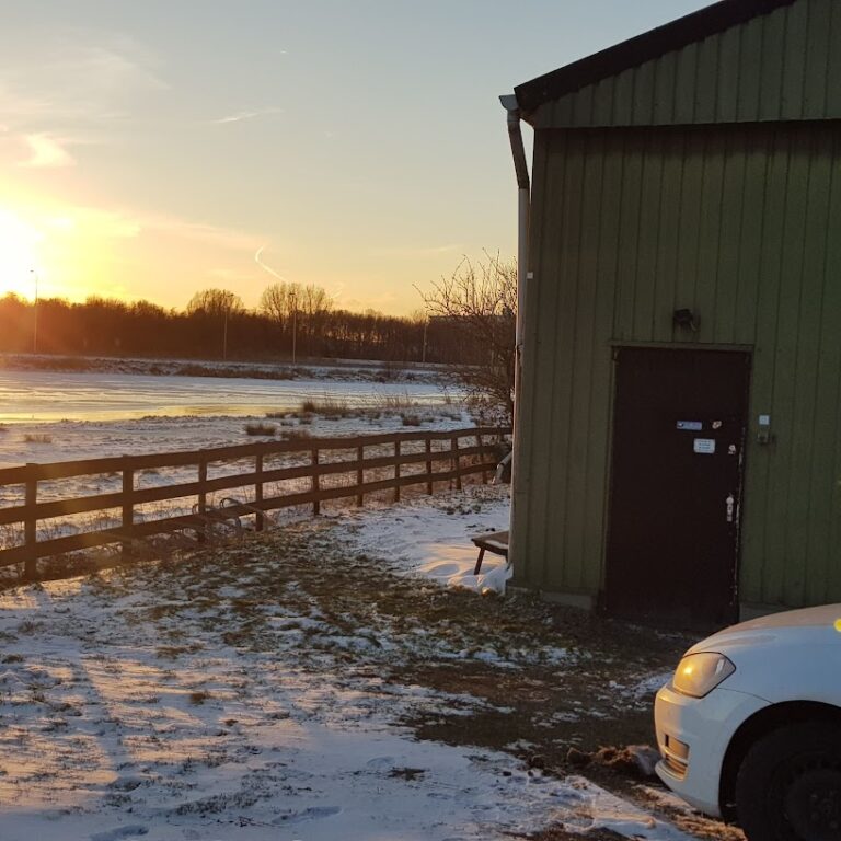 Groene schuur van Stichting UFO bij zonsondergang, met sneeuw rondom